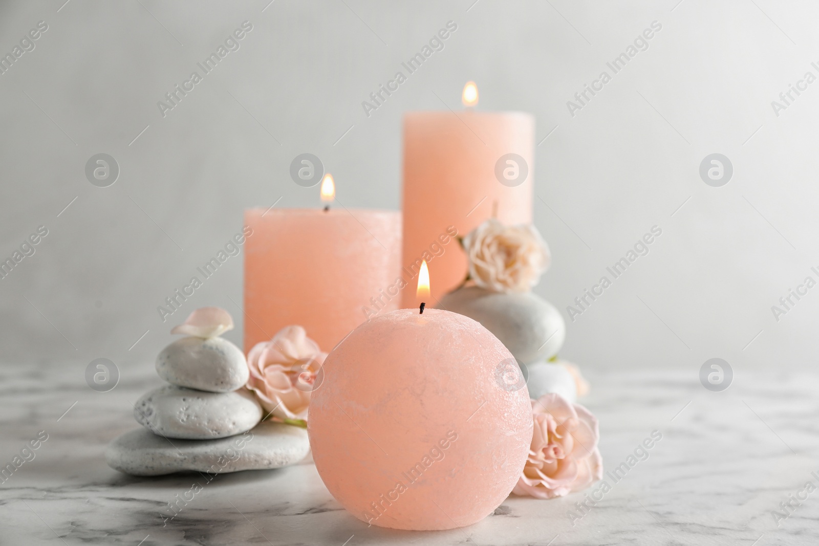 Photo of Burning candles, spa stones and flowers on table. Space for text