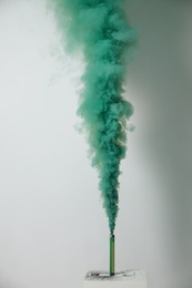 Photo of Bright green smoke bomb on white background