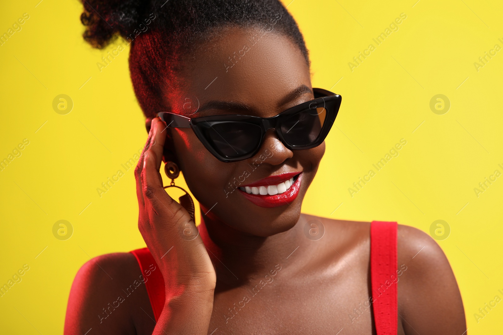 Photo of Fashionable portrait of beautiful happy woman with stylish sunglasses on yellow background