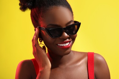 Photo of Fashionable portrait of beautiful happy woman with stylish sunglasses on yellow background