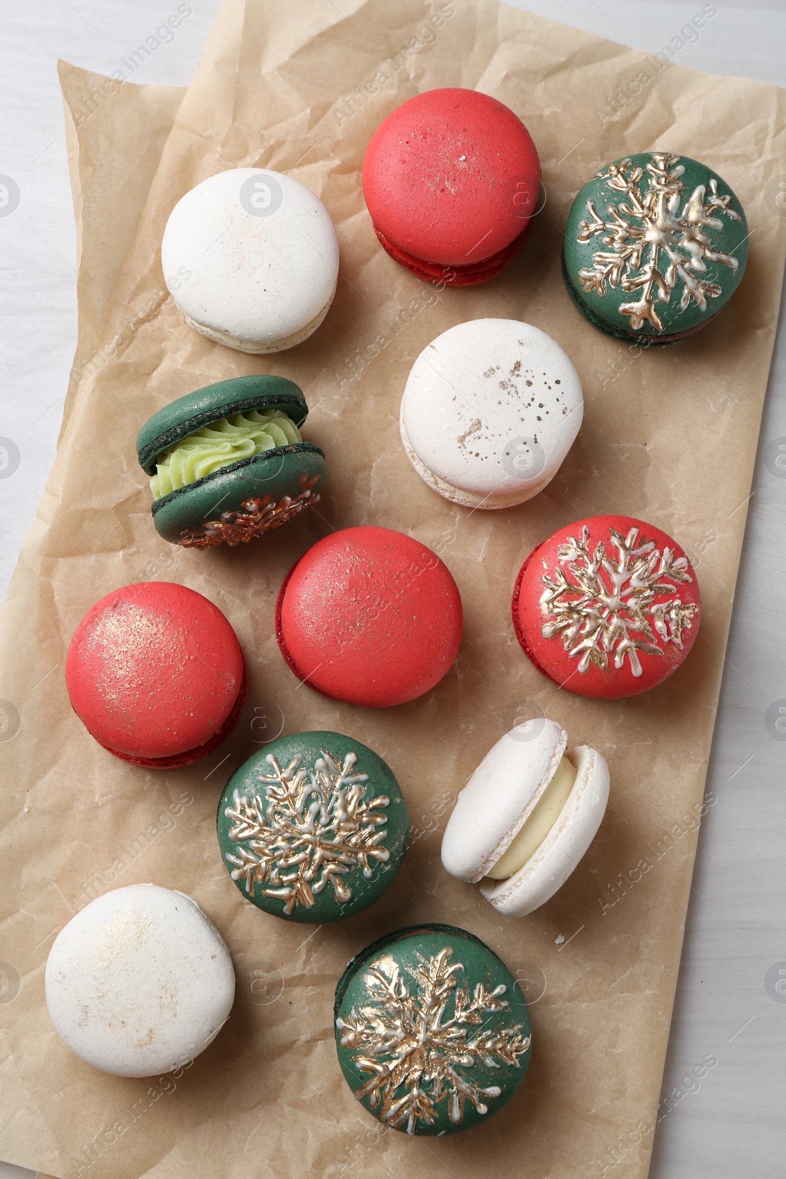 Photo of Different decorated Christmas macarons on white wooden table, flat lay