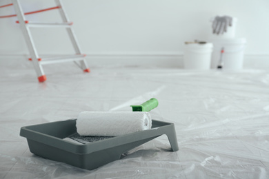 Painting tools on floor in empty room, space for text. Interior renovation