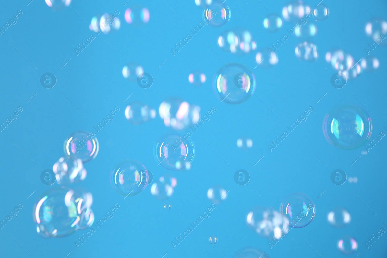 Photo of Beautiful transparent soap bubbles on light blue background