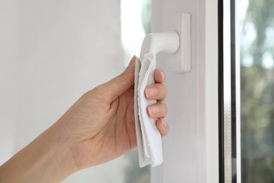 Photo of Woman using tissue paper to open window indoors, closeup