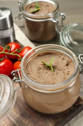 Photo of Glass jar with delicious liver pate on wooden board, closeup