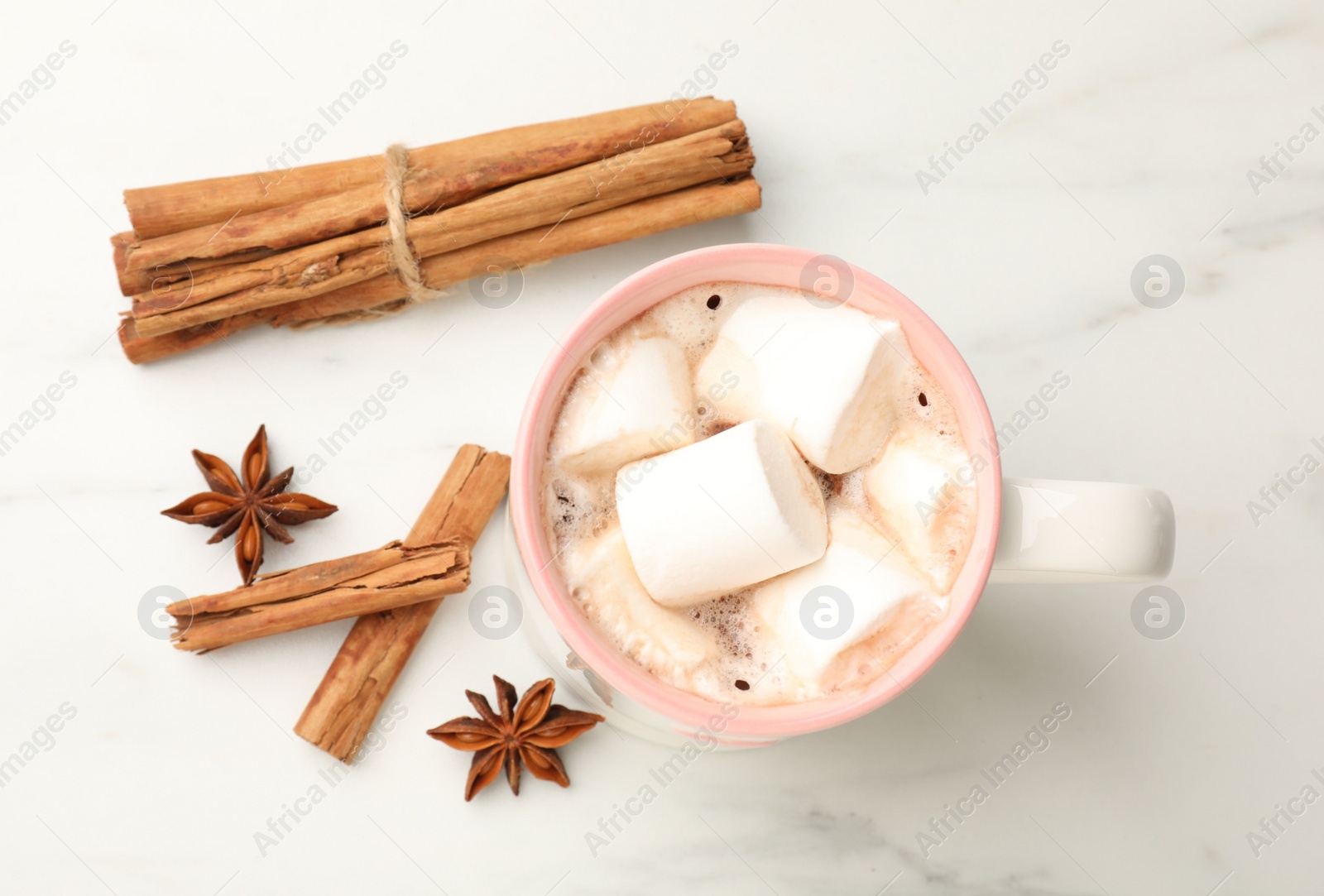 Photo of Tasty hot chocolate with marshmallows and spices on white marble table, flat lay