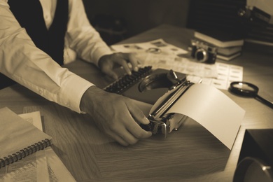 Photo of Old fashioned detective working with typewriter at table in office, closeup