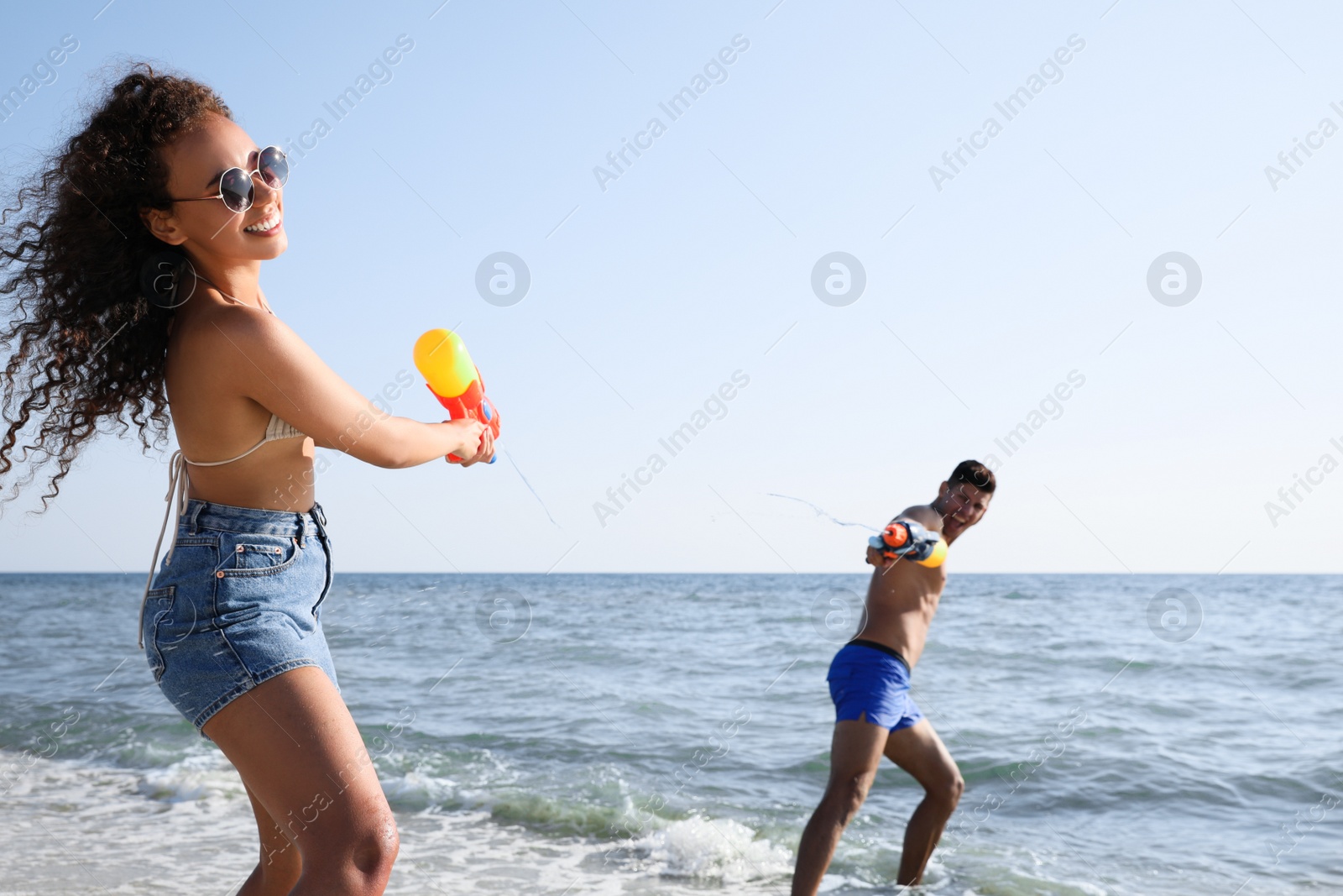 Photo of Couple with water guns having fun on beach