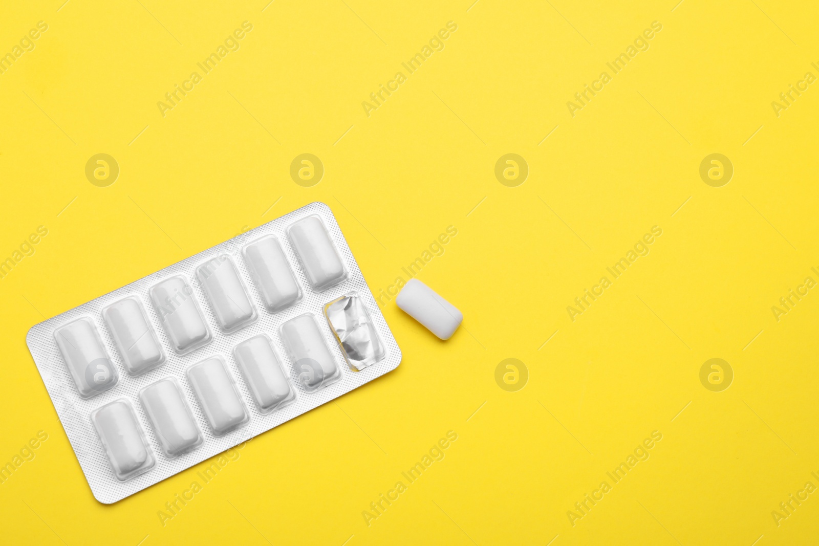 Photo of Blister with chewing gums on yellow background, top view. Space for text