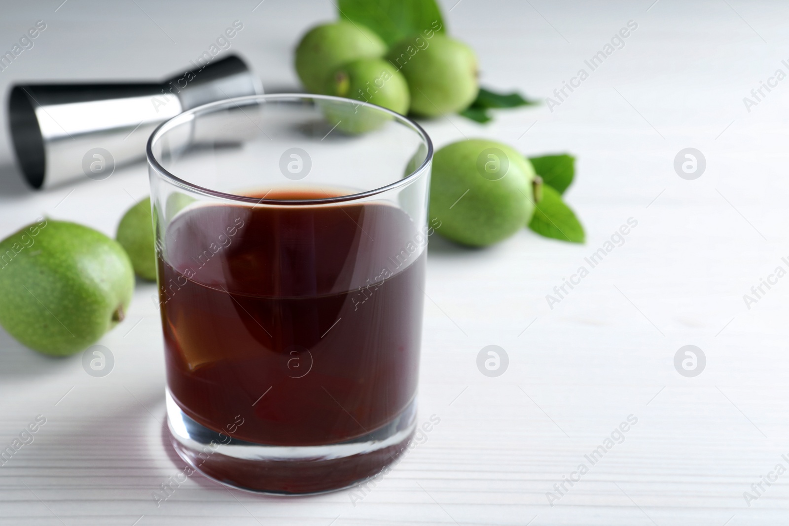 Photo of Delicious liqueur and fresh walnuts on white wooden table, closeup. Space for text