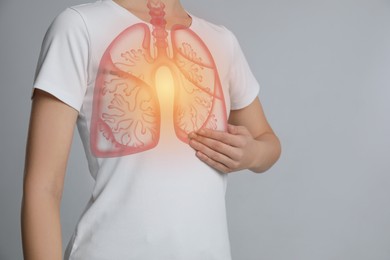 Image of Woman holding hand near chest with illustration of lungs on light grey background, closeup