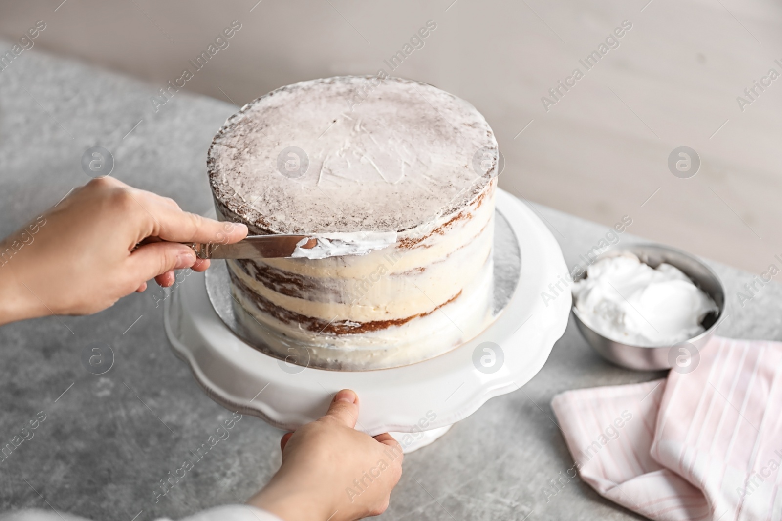 Photo of Woman decorating delicious cake with fresh cream on stand. Homemade pastry