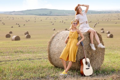 Photo of Beautiful hippie women with guitar in field, space for text