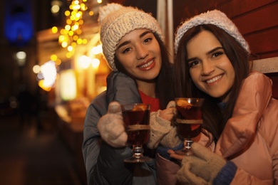 Friends with glass cups of mulled wine at winter fair