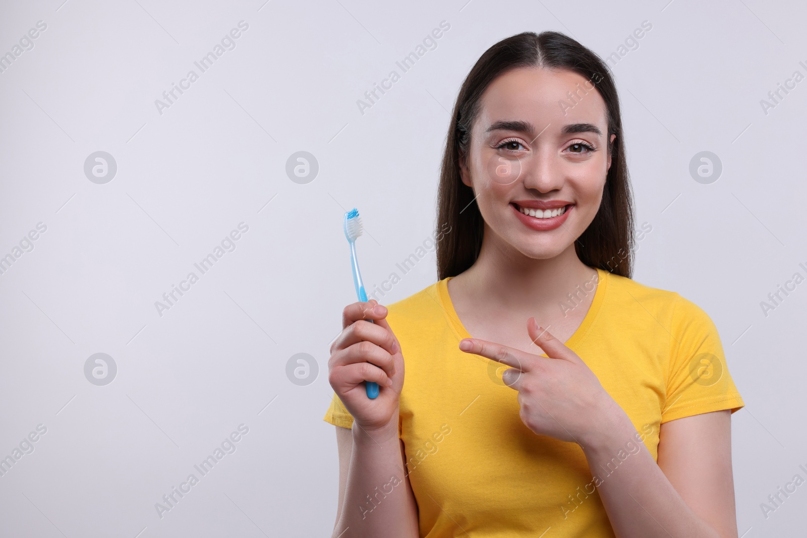 Photo of Happy young woman holding plastic toothbrush on white background, space for text