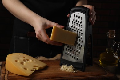 Woman grating cheese at wooden table, closeup