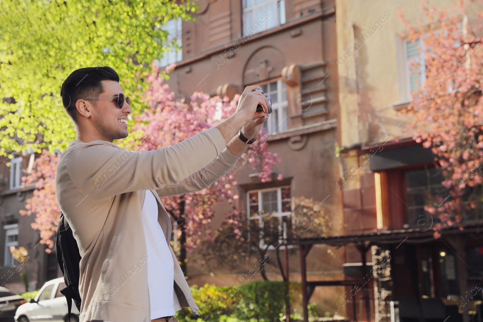 Photo of Happy male tourist with camera on city street