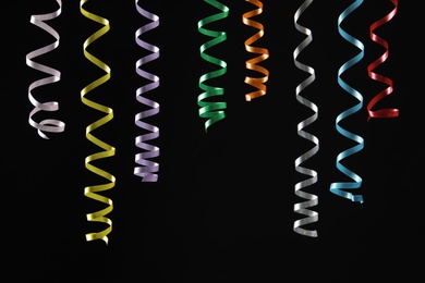 Photo of Many colorful serpentine streamers on black background