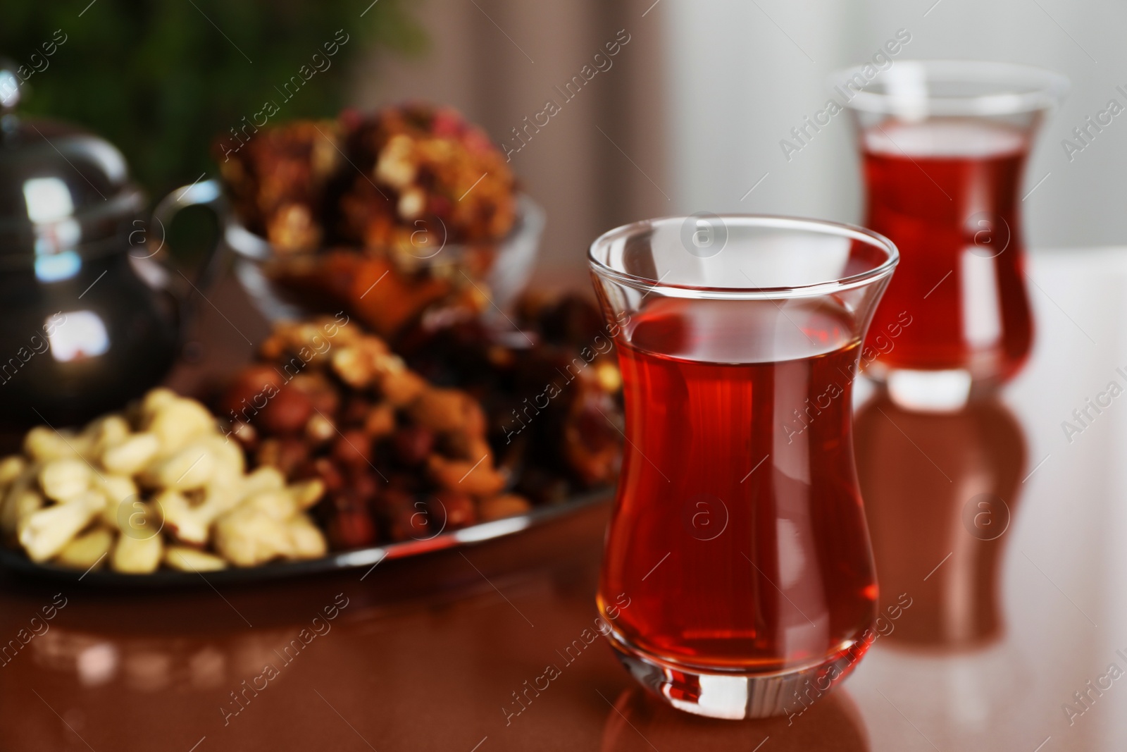 Photo of Glasses with tasty Turkish tea and sweets on brown table indoors