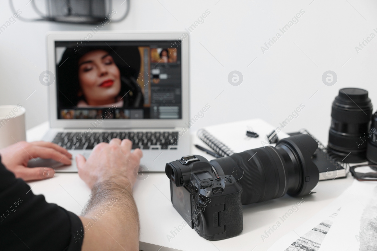 Photo of Professional photographer using laptop at table with digital camera, closeup