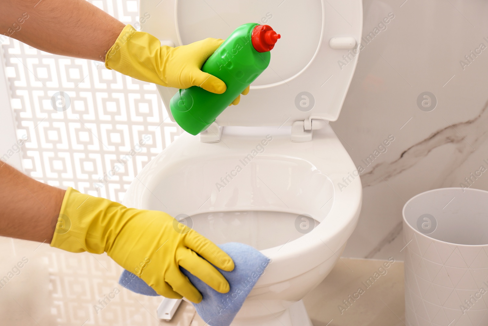 Photo of Man cleaning toilet bowl in bathroom, closeup