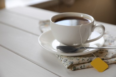 Photo of Tea bag in cup on white wooden table, closeup. Space for text