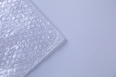 Photo of Transparent bubble wrap on gray background, top view. Space for text