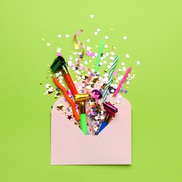 Photo of Beautiful flat lay composition with envelope and festive items on light green background. Surprise party concept