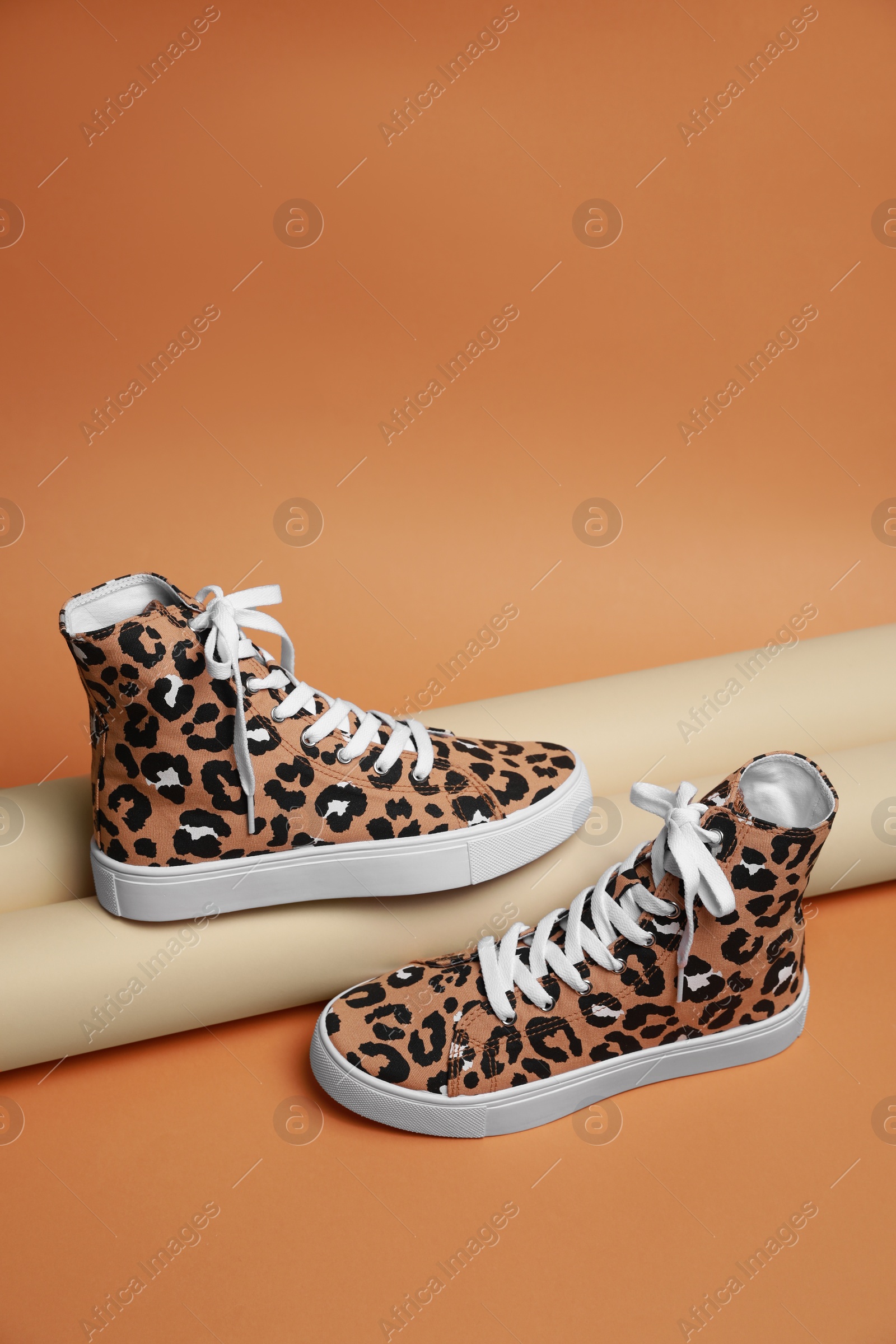 Photo of Stylish presentation of classic old school sneakers on pale orange background