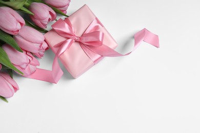 Photo of Beautiful gift box and pink tulip flowers on white background, flat lay. Space for text