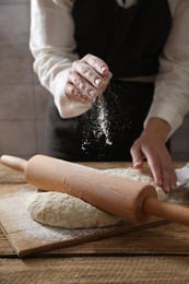 Woman making dough at wooden table, selective focus