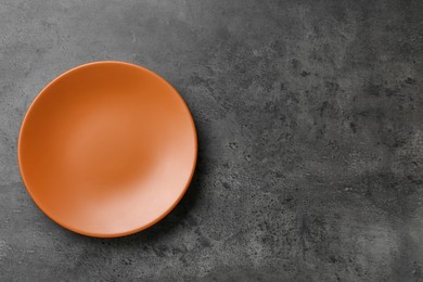 Clean orange plate on grey table, top view. Space for text