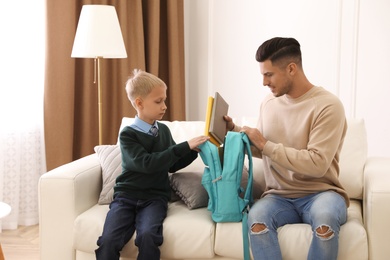 Father helping his little child get ready for school at home