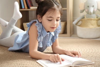 Photo of Little girl reading book on floor at home