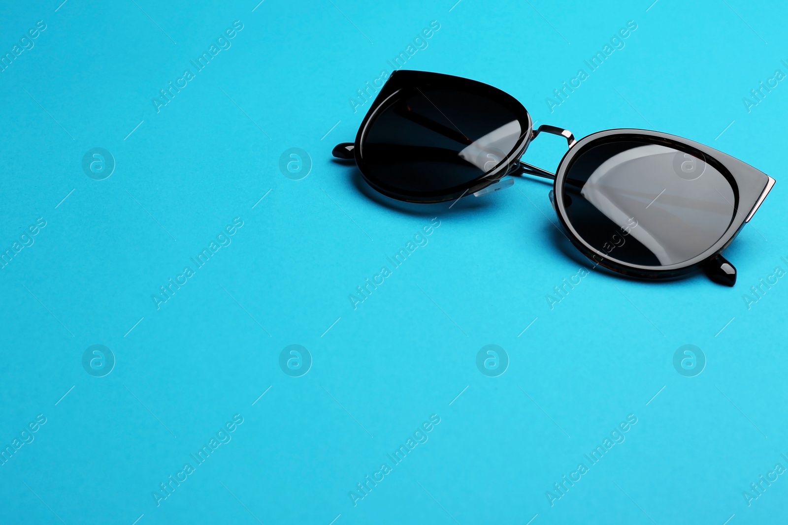 Photo of Stylish sunglasses on blue background, space for text. Fashionable accessory