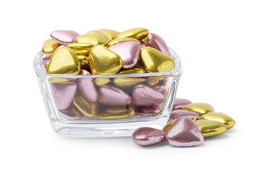 Glass bowl and many delicious heart shaped candies on white background