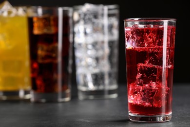Photo of Glass of refreshing soda water with ice cubes on grey table, closeup. Space for text