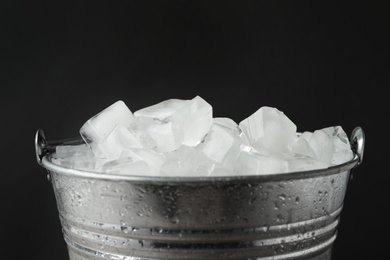 Metal bucket with ice cubes on dark background, closeup