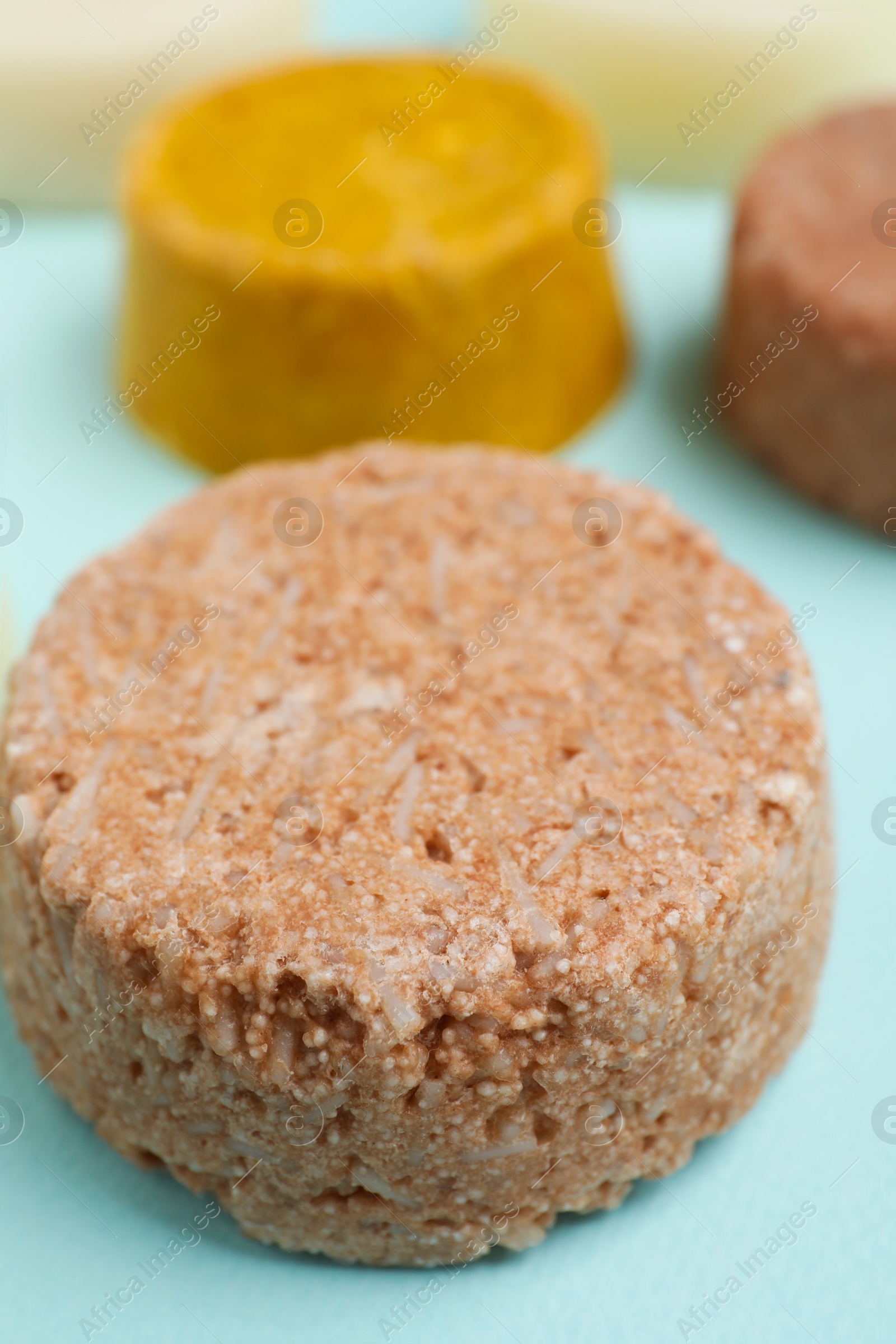 Photo of Group of solid shampoo bar on turquoise table, closeup. Hair care