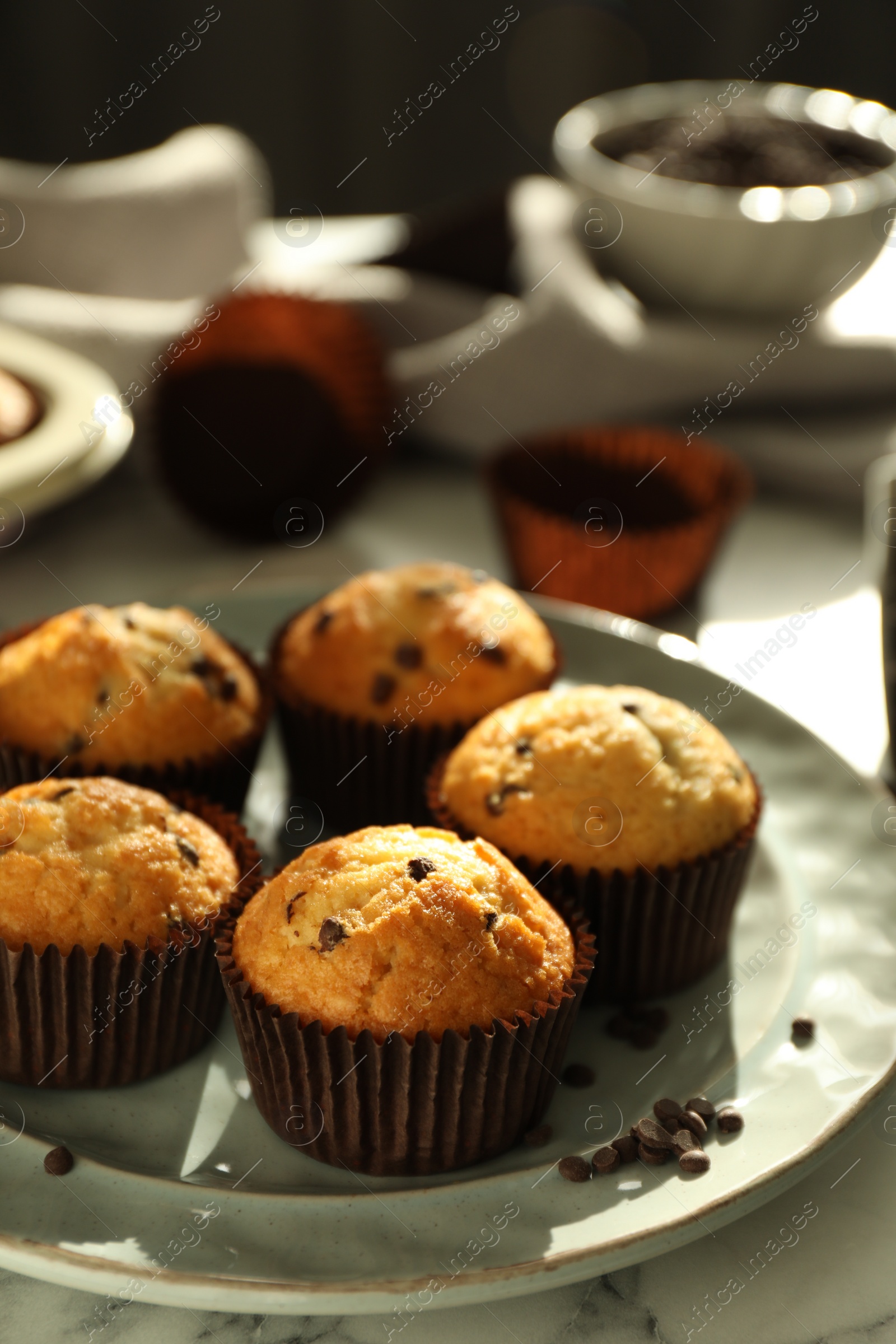 Photo of Delicious sweet muffins with chocolate chips on white marble table