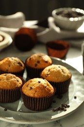 Delicious sweet muffins with chocolate chips on white marble table