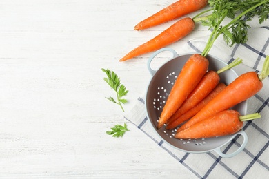 Photo of Flat lay composition with carrots in colander on white table. Space for text