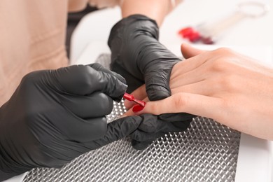 Photo of Professional manicurist working with client at table, closeup