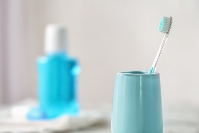 Photo of Cup with toothbrush against blurred background. Dental care