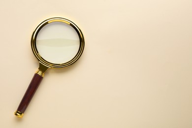 Photo of Magnifying glass on beige background, top view. Space for text