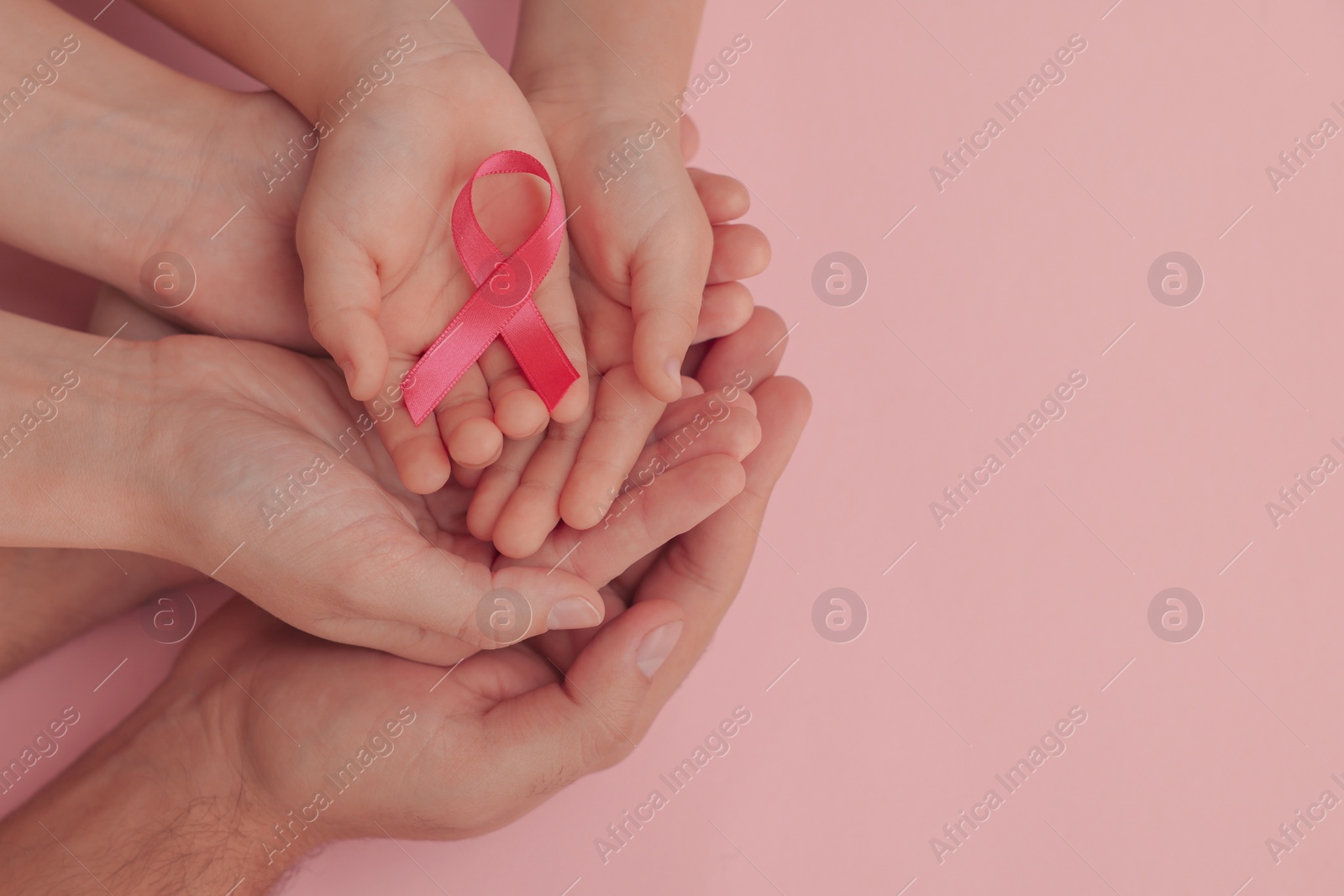 Photo of Family holding pink ribbon on color background, top view with space for text. Breast cancer awareness