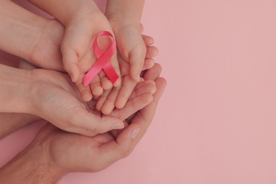 Photo of Family holding pink ribbon on color background, top view with space for text. Breast cancer awareness