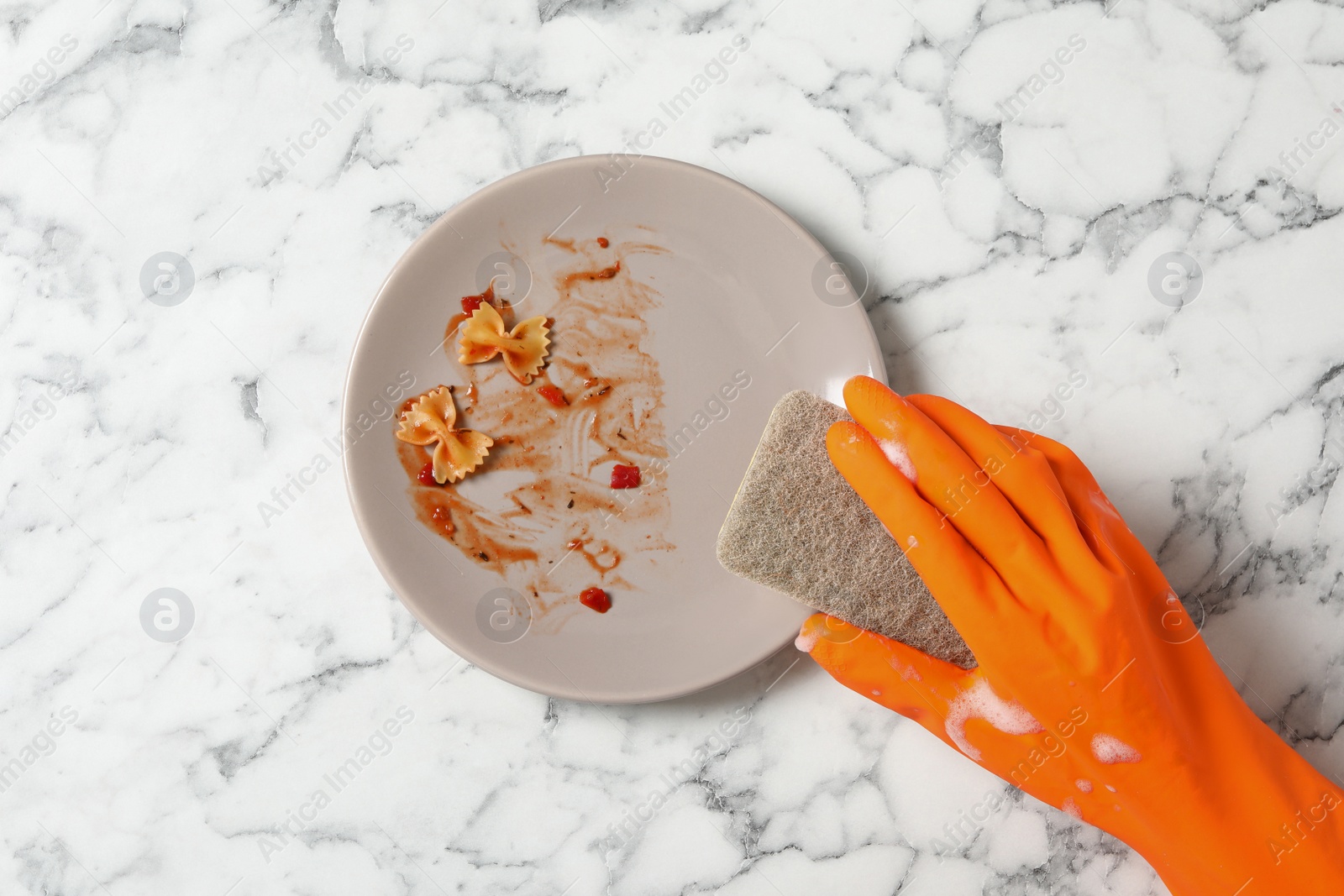 Photo of Woman washing dirty plate at white marble table, top view