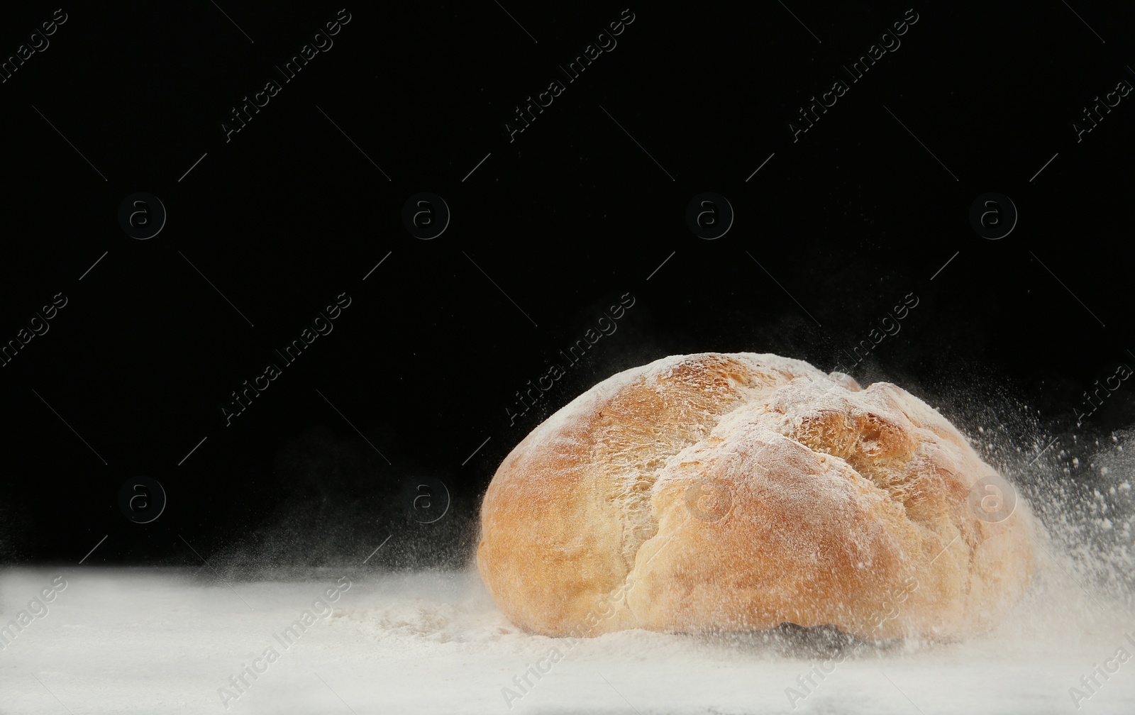 Photo of Loaf of bread on table against dark background. Space for text