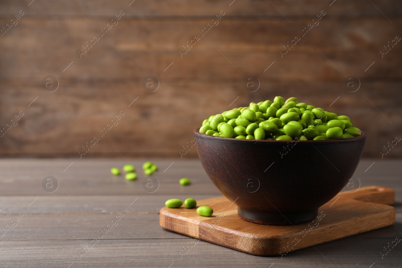 Photo of Bowl of delicious edamame beans on wooden table, space for text